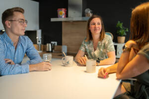 3 personnes autour d'une table entrain de discuter et de boire de l'eau